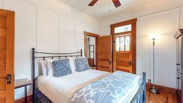 Ein Schlafzimmer mit Bett, Deckenventilator, Holztür und Stehlampe.