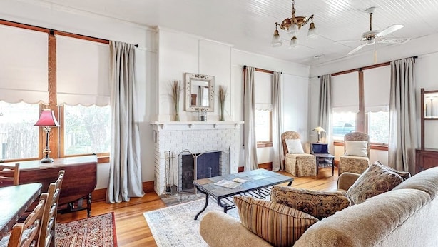 A living room with a fireplace, a dining area, and a sofa. - Enchanting home with fireplace, full kitchen, patio, central AC, & washer/dryer (Fredericksburg)