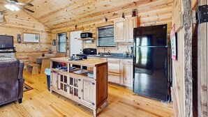 A wooden cabin interior with a kitchen, dining area, and a sofa. - Dog-friendly gem on 11 acres w/valley views, deck, gas grill, fireplace (Fredericksburg)