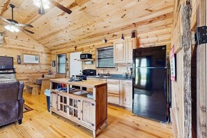Ein Holzblockhaus im Inneren mit Küche, Essbereich und einer Couch.