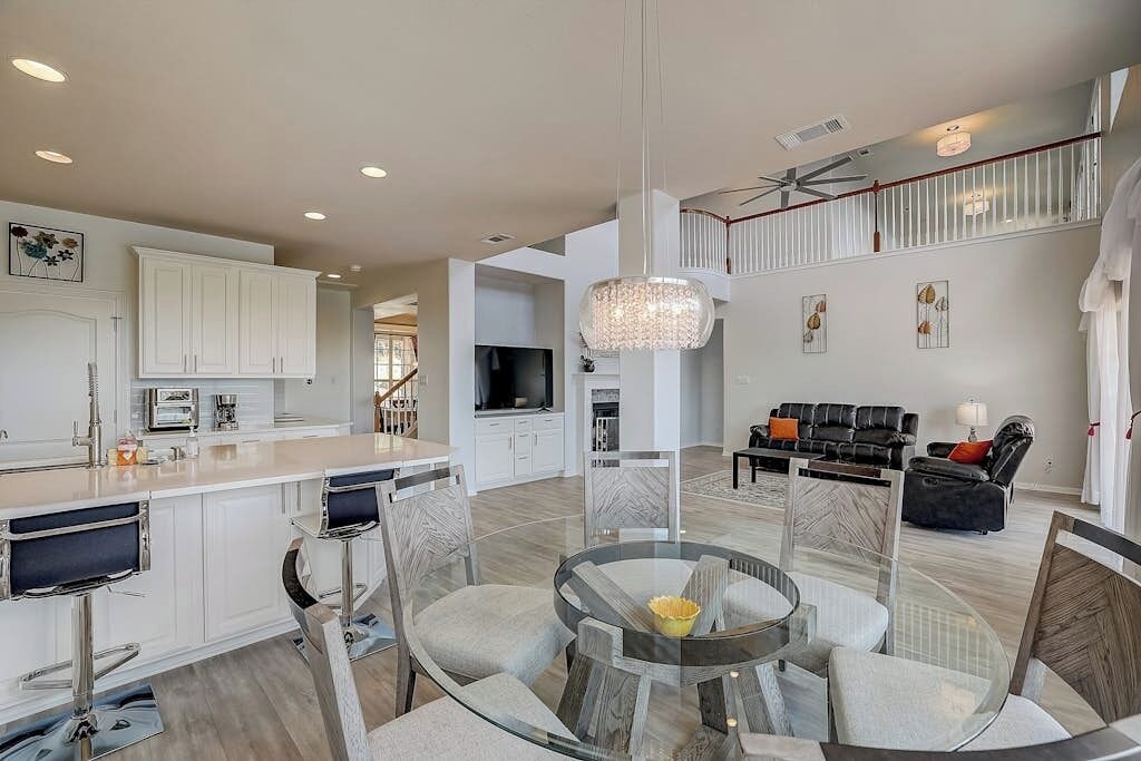 A spacious living area with a round glass table, modern furniture, and a staircase leading to an upper level.