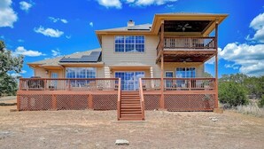 A two-story house with a balcony, a deck, and a staircase leading to the entrance. - Spacious, dog-friendly home with two decks, views, grill, W/D & community pool (Lago Vista)