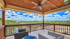 A covered outdoor area with wicker furniture, a ceiling fan, and a view of a green landscape. - Spacious, dog-friendly home with two decks, views, grill, W/D & community pool (Lago Vista)