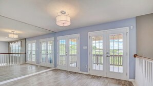 A spacious room with a wooden floor, large windows, and a balcony. - Spacious, dog-friendly home with two decks, views, grill, W/D & community pool (Lago Vista)