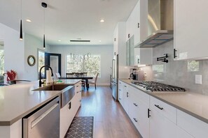 Una cocina moderna con una isla central, electrodomésticos integrados y un comedor con vistas.