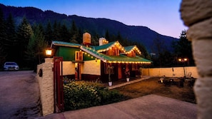 A rustic lodge with a green roof, stone walls, and string lights.