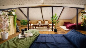 A tented room with a bed, a table with chairs, and potted plants. - The Alpine Hut (Manali)