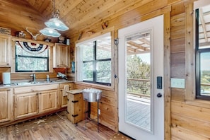 Ein Holzblock-Interieur mit einer Küche, einer Tür zu einer Terrasse und einer Deckenleuchte.