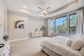A bedroom with a bed, a ceiling fan, a window, and a painting on the wall. - Exquisite dog-friendly home with balcony, enclosed yard, central AC, & W/D (Jonestown)