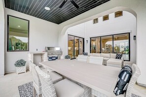 A modern outdoor dining area with a long table, wicker chairs, and a grill. - Exquisite dog-friendly home with balcony, enclosed yard, central AC, & W/D (Jonestown)