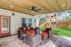 Eine überdachte Terrasse mit Korbmöbeln und einem hölzernen Deckenventilator.