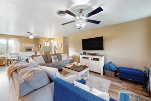 A living room with a ceiling fan, a flat-screen TV, a sofa, a coffee table, and a television cabinet. - Dog-friendly, secluded home 2 miles to Main St. with firepit, gazebo, & BBQ pit (Fredericksburg)
