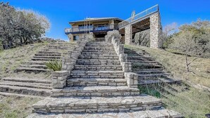 A stone staircase leading to a modern building with a balcony.