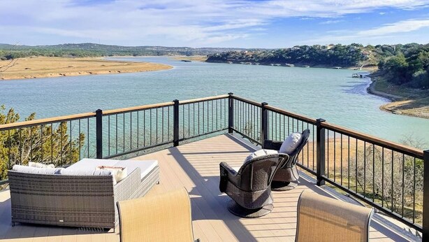 A deck with wicker furniture overlooking a river.