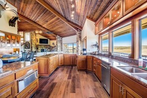 Una cocina amplia con armarios de madera, un muro decorativo de piedra y ventanas grandes que ofrecen una vista.