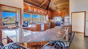 A spacious kitchen with granite countertops, wooden cabinets, and a large island.