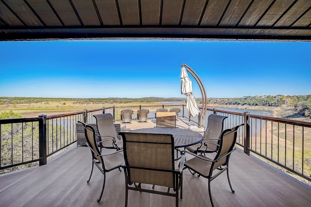 A covered outdoor seating area with a table and chairs, overlooking a scenic landscape.