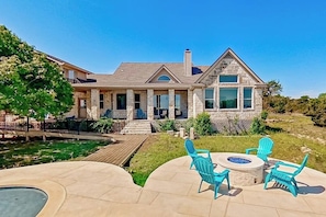 A house with a stone exterior, a deck, and outdoor seating with chairs.