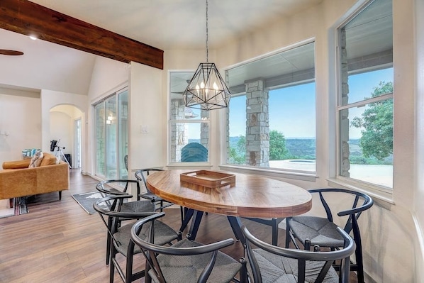 A dining area with a round wooden table, six chairs, and a hanging light fixture.