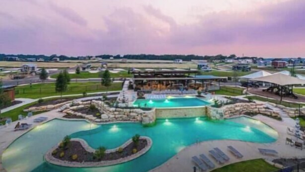 Ein Resort mit großem Schwimmbecken, Sitzgelegenheiten im Freien und einem überdachten Bereich.