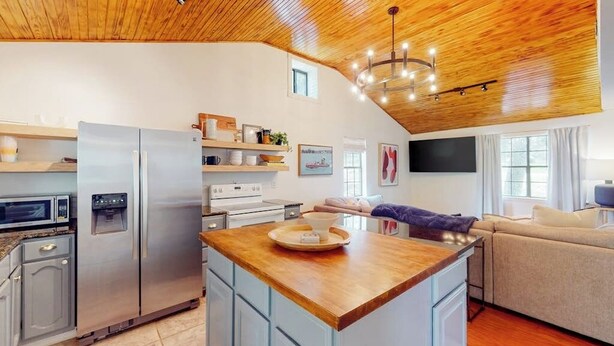 Una cocina moderna con una isla central, electrodomésticos integrados y techo de madera.