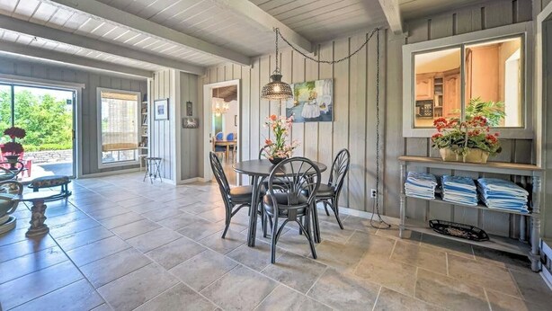 A spacious room with a dining table and chairs, a hanging light fixture, and a view of the outdoors. - Snowbird-friendly house with game room, full kitchen, balcony, & W/D (Kerrville)