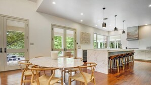 A modern kitchen with a round dining table, wooden chairs, a bar area, and large windows. - Inviting waterfront home with pool, patio, fireplace, W/D, & dog-friendly (Hunt)