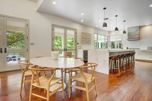 A modern kitchen with a round dining table, wooden chairs, a bar area, and large windows. - Inviting waterfront home with pool, patio, fireplace, W/D, & dog-friendly (Hunt)