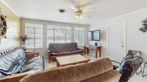 Ein Wohnzimmer mit Deckenventilator, Fernseher und einer Couch.