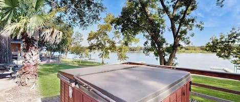 Un bain à remous sur une terrasse en bois avec vue sur le lac.