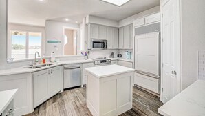 Una cocina moderna con armarios blancos, una isla central, un microondas y un refrigerador.