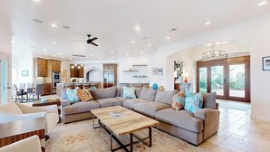 A spacious living area with a large sectional sofa, a coffee table, and a kitchen in the background. - Luxe lakefront retreat with private pool, spa, lakeside terrace, gourmet kitchen (Horseshoe Bay)