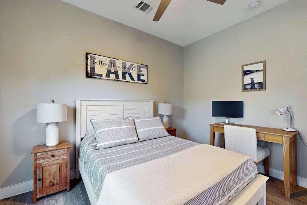A bedroom with a bed, bedside tables, a desk, and a chair.