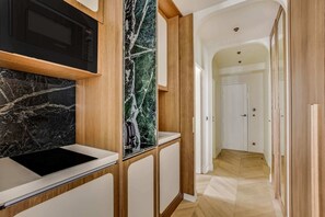 Eine moderne Küche mit einer schwarzen Mikrowelle, einer Marmor-Spritzschutzwand und Holzschränken.