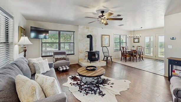 A living room with a sofa, a coffee table, a fireplace, and a dining area. - Idyllic home with fire pit, gazebo, patio, & amazing deck views - dog-friendly (Fredericksburg)