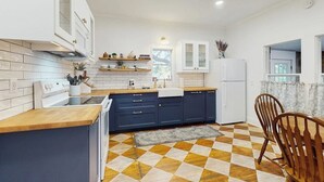 Eine moderne Küche mit Schachbrettboden, Holzschränken und einem Essbereich mit Stühlen.
