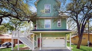 A two-story house with a front porch, a garage, and a staircase leading to the entrance.