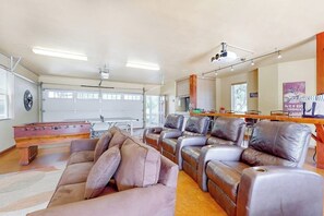 Amplia sala de estar con mesa de billar, sillones de cuero y puerta de garaje.