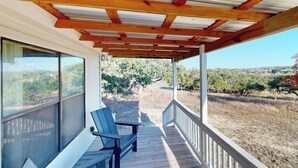 Un espacio al aire libre cubierto con vigas de madera, un banco y vistas a un viñedo.