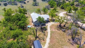 A house surrounded by trees with a dirt path leading to it. - Cozy ranch home w/full kitchen, living room, hot tub, pet-friendly & fireplace (Fredericksburg)