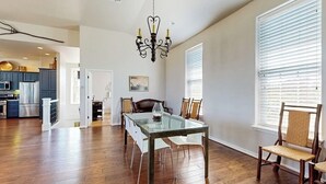 A spacious dining area with a glass table, wooden chairs, and a chandelier. - Spicewood Lake Retreat | Pool + Shuffleboard (Spicewood)