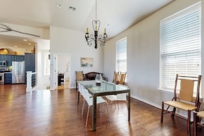 A spacious dining area with a glass table, wooden chairs, and a chandelier. - 4-bedroom spacious home with guest house & pool, located on 9 acres of land (Spicewood)
