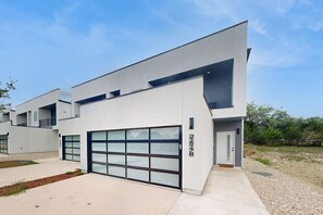 Ein modernes, zweistöckiges Haus mit Garage, flachem Dach und kleinem Balkon.