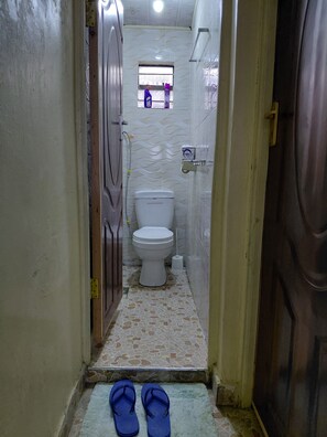 Ein schmaler Flur, der zu einem Badezimmer mit Toilette, einem Fenster und einem Handtrockner führt.