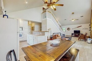 A spacious living area with a wooden dining table, a staircase, and a kitchen area.