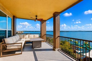 A balcony with a sofa, a table, and a view of a body of water.