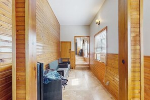 A hallway with wooden paneling, a seating area with chairs and a table, and a window with blinds. - Waterfront house on Lake LBJ with full kitchen, patio, pool table & dog-friendly (Granite Shoals)