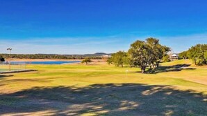 A golf course with a water body, trees, and a clear sky. - Scenic riverfront home w boat access, private pool/hot tub - close to shopping (Lago Vista)