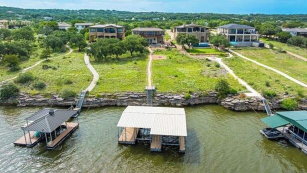 A lakeside property with floating structures, a dock, and a path leading to houses. - Scenic riverfront home w boat access, private pool/hot tub - close to shopping (Lago Vista)