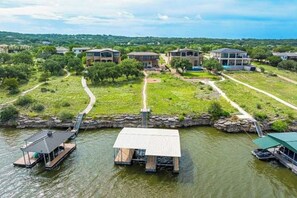A lakeside property with floating structures, a dock, and a path leading to houses. - Scenic riverfront home w boat access, private pool/hot tub - close to shopping (Lago Vista)